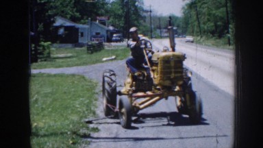 1958: a man driving a yellow tractor down a road NEBRASKA