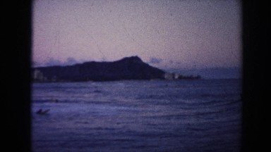 1961: View from a Boat Showing People in Water with Surfboards and Mountains