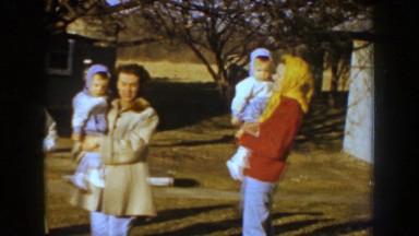 1959: two women holding identically dressed children with three other women and