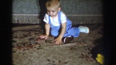 1959: a blond haired toddler crawling around on the carpet then standing and