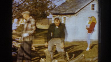 1959: family talking and watching father figure load car with chopped wood with