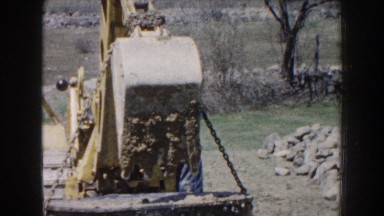 1959: a worker lifts an underground tank from the ground using a backhoe