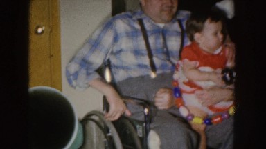 1955: disabled man holds happy bouncy child NEBRASKA