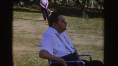 1955: man in wheelchair watching kids playing with toy tractor and croquet