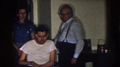 1957: a man comes to stand behind another man in a wheelchair NEBRASKA