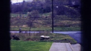 1956: a blue car passing fast through a village road with amazing scenery