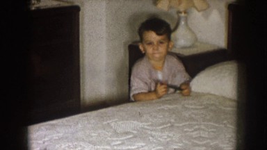 1957: playing a baby in the bed and sit and up having black color band in his