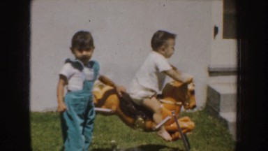 1952: two small kids are playing in toy horse outside the house CALIFORNIA
