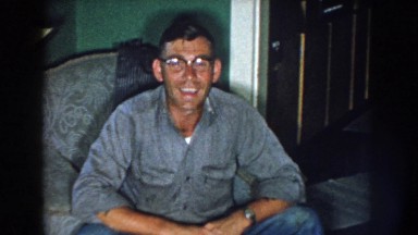 1959: a middle aged, blue collar man sits comfortably in his chair, sleeves