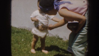 1952: mother adjusting toddler's diaper outside. CALIFORNIA