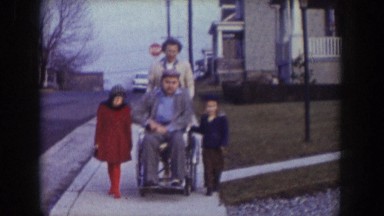 1957: man in wheelchair being pushed by a woman with a child on either side of