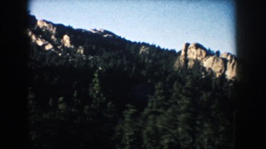 1953: gray mountains with slanting ridges tower above forests and point toward