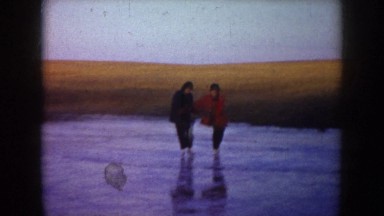 1953: Three People Enjoying Skating on a Frozen Lake Accompanied by a Dog North