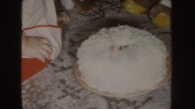 1955: a little girl playing on the floor with a cake and its small candle
