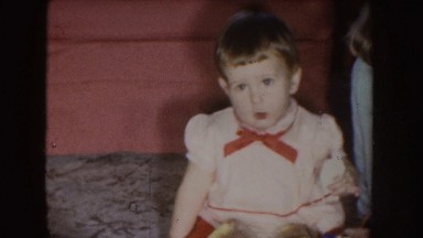 1955: a chubby baby with a red bow is looking into the camera, crawling around