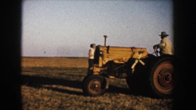 1953: a woman with glasses smiling and some farmers harvesting SOUTH DAKOTA