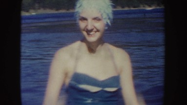 1954: two women wearing swimming caps and a boy swim in the designated swimming