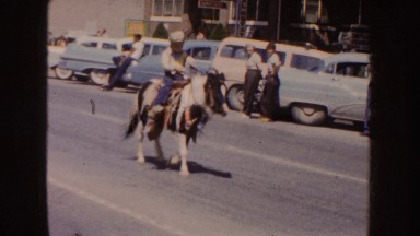 1954: a boy riding a pony walks in front of the public lining the street SOUTH