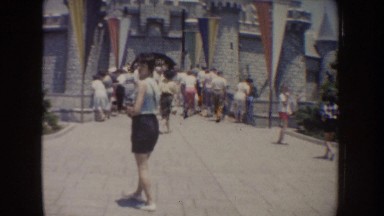 1962: A Woman Poses in Front of Large Castle Among Tourists