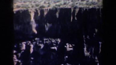 1957: rock cliff and adjacent rocky steep slopes with forest in background