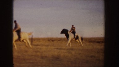 1955: two horsemen having a race in a field, wherein the white horse is on the