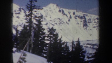 1957: peaks and slopes adjacent to a lake and a woman waving OREGON