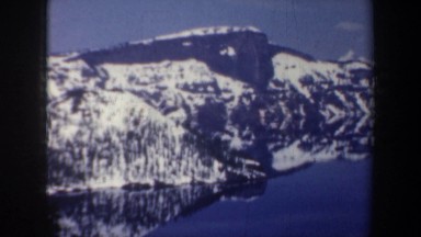 1957: a short left panning scene of a mountain with a body of water below,