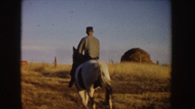 1955: a man and woman riding on the horses through a grass field IDAHO