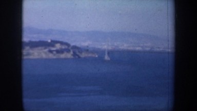 1957: partial view of a bridge lifted over the water, a city being seen in the