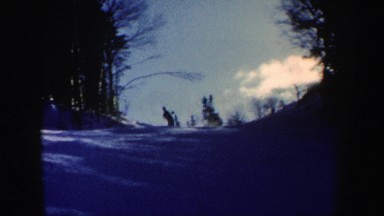 1962: skier sliding down a slope to stop in front of his two other fellow skiers