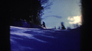 1962: a man skis down a snowy slope appearing to hit two men standing in his