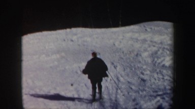 1962: skier skiing down a moderate slope in between conifers and ski lift