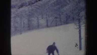 1962: multiple warmly dressed people skiing around a curve on a snowy and tree