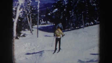 1962: two people skiing on the snow slowly and a red winch rope car VERMONT