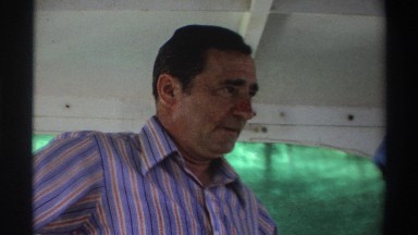 1969: Man in Fishing Boat Smiling and Talking to Lady with Freshly Caught Bass