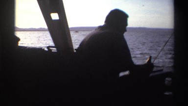 1969: Man on Boat in Ocean with Beer and Fishing Pole in Holder