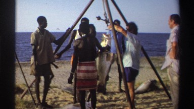 1969: the fishermen hanging a caught fish on a tripod on the beach NIGERIA