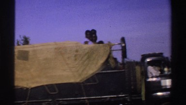 1969: a truck with a tarp partially covering the cargo bed transports black men