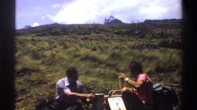 1969: Two Men Eating Lunch in a Field with Packs Sudan