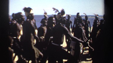 1969: a large group of black people dressed in tribal gear holding hands and