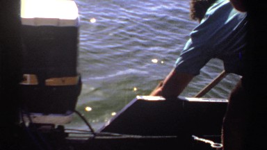 1969: man leaning over boat edge to reach into the water SUDAN