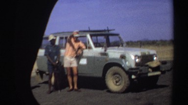 1969: Three Men Standing by a Jeep, One Waving, as Seen from the Vantage of a