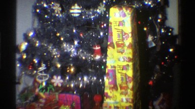 1975: colorfully wrapped christmas presents racked beside the christmas tree