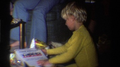 1975: family gathered in living room, children opening presents with little girl