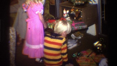 1975: a young boy and girl inspect their unopened gifts on christmas morning