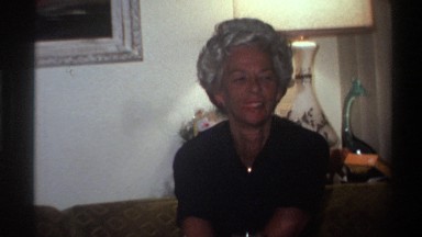1975: old women chatting inside a house, sitting on a sofa folding clothes