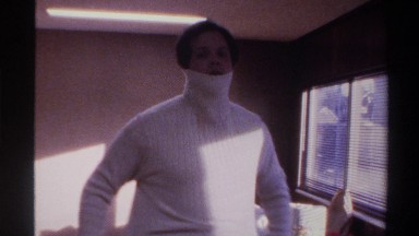 1975: man putting on white turtleneck sweater and dancing for the camera FLORIDA