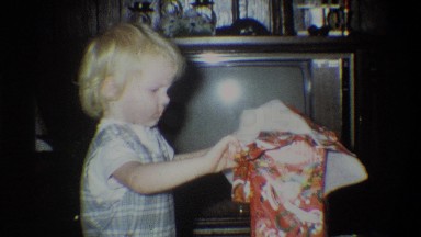 1973: a young, blonde haired boy joyfully rips the wrapping paper off a gift