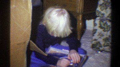 1973: A Blond Haired Boy Opens a Christmas Present While Sitting on the Living Room Floor