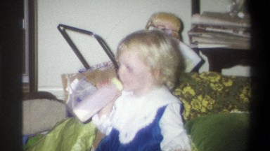 1973: toddler with baby bottle lounges with grandfather NEW YORK